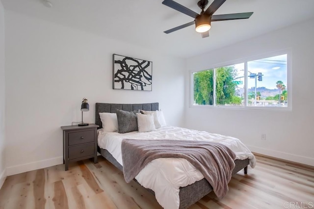 bedroom featuring baseboards, light wood-type flooring, and ceiling fan