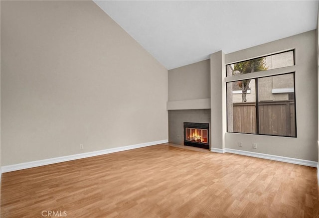 401 Deerfield Ave Unit 84, Irvine, CA 92606 - unfurnished living room featuring light wood-style flooring, a fireplace with flush hearth, baseboards, and lofted ceiling