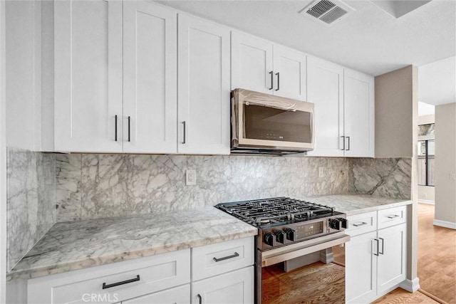401 Deerfield Ave Unit 84, Irvine, CA 92606 - kitchen featuring stainless steel appliances, light stone countertops, white cabinetry, and backsplash