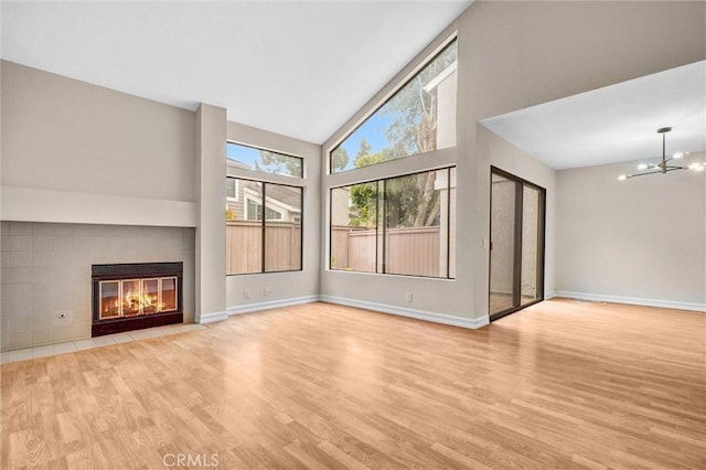 401 Deerfield Ave Unit 84, Irvine, CA 92606 - unfurnished living room featuring high vaulted ceiling, wood finished floors, a tile fireplace, baseboards, and a chandelier