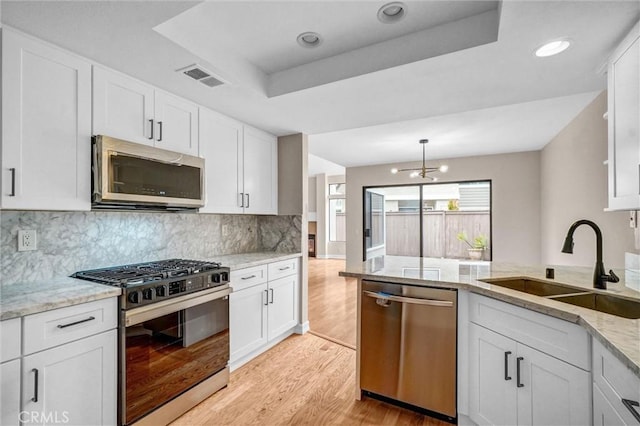 401 Deerfield Ave Unit 84, Irvine, CA 92606 - kitchen featuring stainless steel appliances, a sink, light wood-style floors, a tray ceiling, and white cabinets