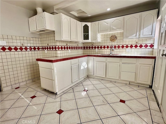 1516 W Burnett St, Long Beach, CA 90810 - kitchen featuring a sink, tile counters, light tile patterned floors, white cabinetry, and tile walls