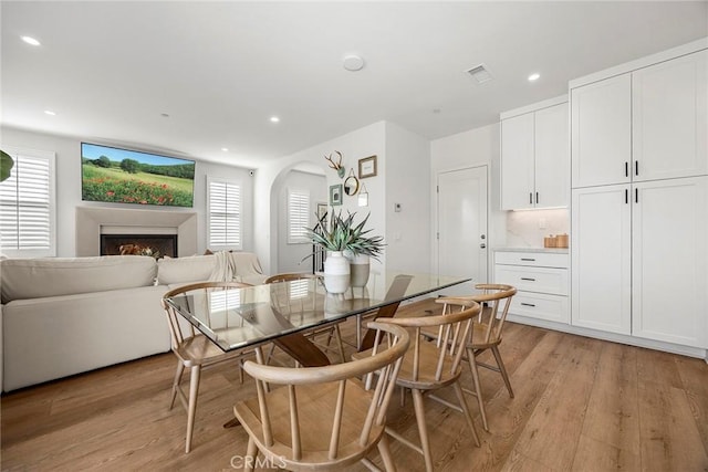 214 Canterbury, Irvine, CA 92618 - dining room featuring arched walkways, light wood-style flooring, recessed lighting, and a lit fireplace
