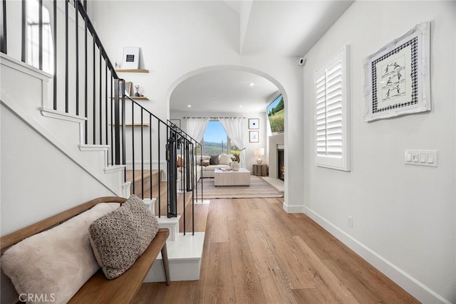 214 Canterbury, Irvine, CA 92618 - foyer entrance featuring arched walkways, wood finished floors, baseboards, stairs, and a lit fireplace