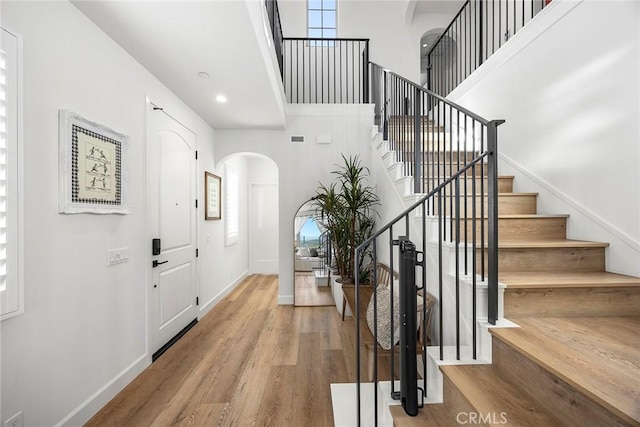 214 Canterbury, Irvine, CA 92618 - entryway with arched walkways, wood finished floors, stairs, baseboards, and a towering ceiling