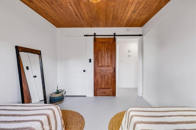 bedroom featuring wooden ceiling, baseboards, a barn door, and concrete floors
