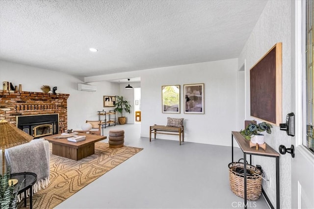 living room featuring a wall unit AC, a textured ceiling, concrete flooring, a fireplace, and recessed lighting