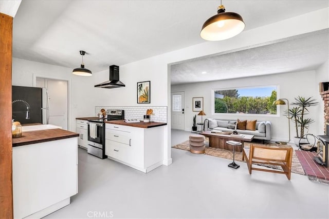 kitchen with stainless steel range with electric cooktop, wall chimney range hood, wooden counters, freestanding refrigerator, and white cabinetry
