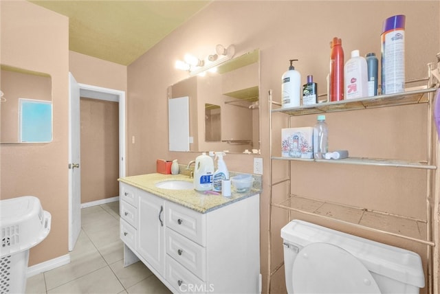 bathroom featuring a sink, tile patterned flooring, baseboards, and toilet