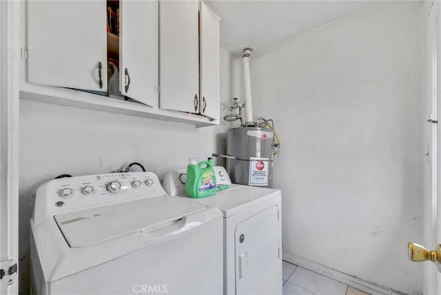 laundry area featuring strapped water heater, cabinet space, washer and clothes dryer, and light tile patterned floors