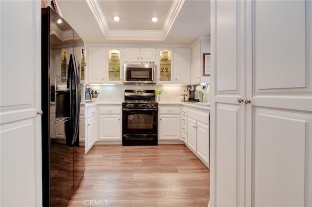 8646 Butte Cir Unit 604B, Huntington Beach, CA 92646 - kitchen featuring black appliances, a raised ceiling, crown molding, light countertops, and light wood-style floors