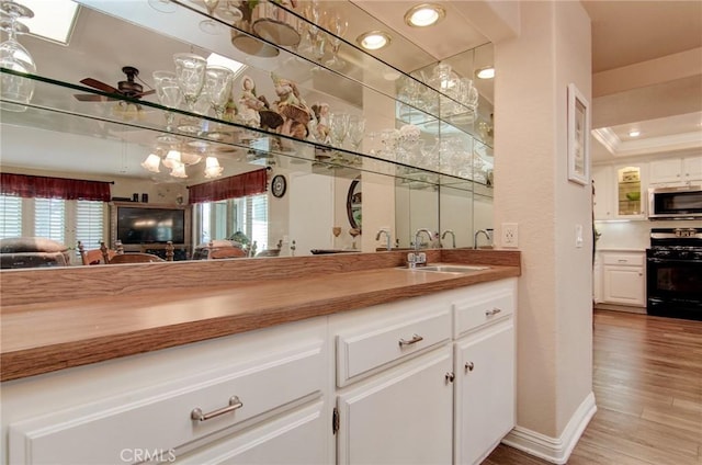 8646 Butte Cir Unit 604B, Huntington Beach, CA 92646 - indoor wet bar featuring gas stove, stainless steel microwave, light wood-type flooring, baseboards, and ceiling fan