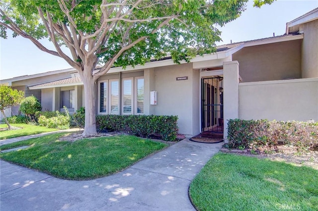 8646 Butte Cir Unit 604B, Huntington Beach, CA 92646 - view of exterior entry with stucco siding and a yard