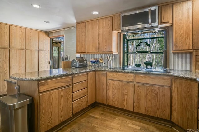 15390 Las Planideras, Rancho Santa Fe, CA 92067 - kitchen with wood finished floors, a peninsula, black electric cooktop, dark stone countertops, and recessed lighting