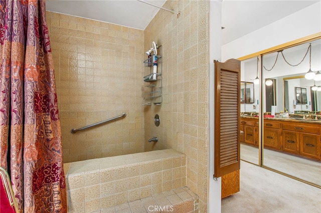 full bath with a tile shower and vanity