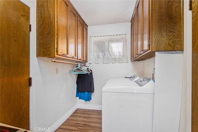 clothes washing area featuring independent washer and dryer, baseboards, cabinet space, and wood finished floors