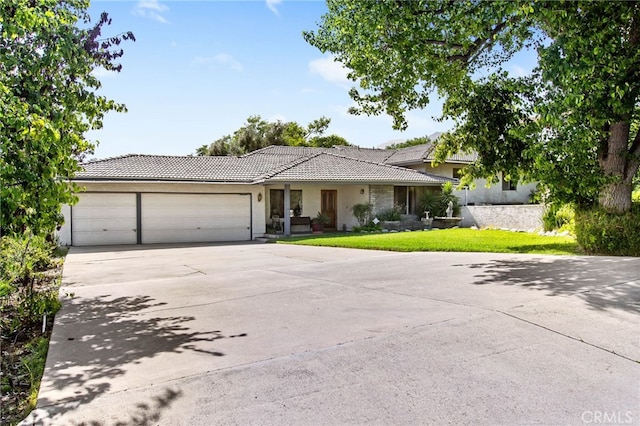 ranch-style home featuring a tiled roof, a garage, concrete driveway, stucco siding, and a front yard