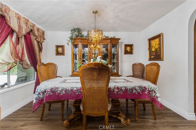 dining area with a chandelier, baseboards, arched walkways, and wood finished floors