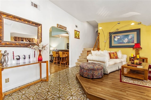 living room with arched walkways, stairway, wood finished floors, and baseboards