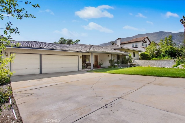 view of front of home featuring a tile roof, a garage, concrete driveway, a front lawn, and stucco siding