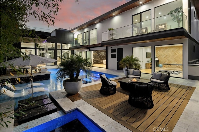 38221/2 Laurel Canyon Blvd, Studio City, CA 91604 - back of house at dusk with a fire pit, a balcony, an outdoor pool, and stucco siding