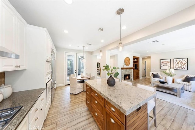 107 Plaza Via Sol, San Clemente, CA 92673 - kitchen featuring open floor plan, a kitchen island, wood tiled floors, brown cabinets, and white cabinets