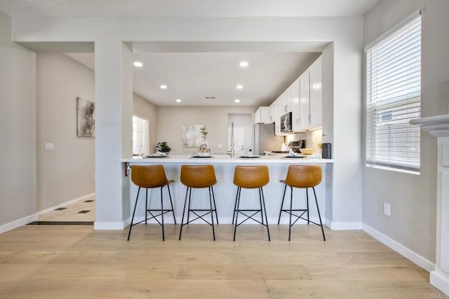26149 Manzanita St, Murrieta, CA 92563 - kitchen with appliances with stainless steel finishes, a peninsula, white cabinetry, a kitchen bar, and recessed lighting