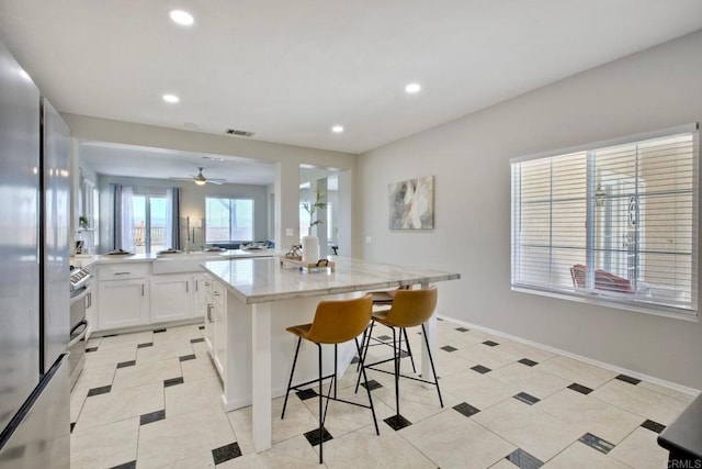 26149 Manzanita St, Murrieta, CA 92563 - kitchen featuring a kitchen bar, light stone countertops, white cabinets, recessed lighting, and stainless steel refrigerator