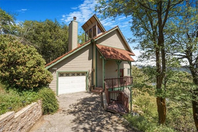 1033 Nadelhorn Dr, Lake Arrowhead, CA 92352 - view of property exterior featuring asphalt driveway, a chimney, a garage, and a porch