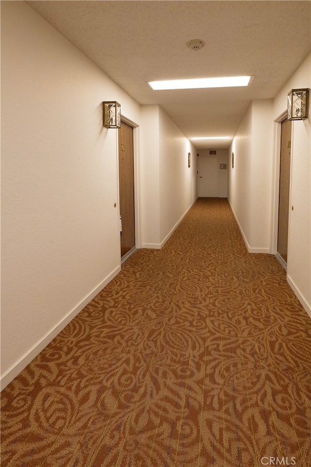 hallway featuring carpet floors and baseboards