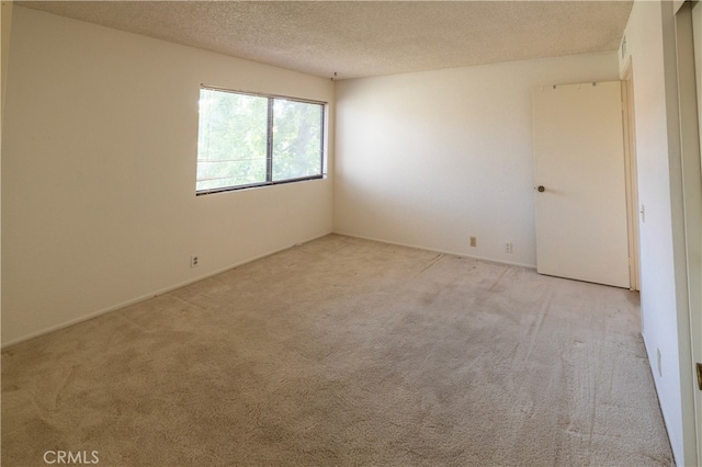 carpeted empty room featuring a textured ceiling