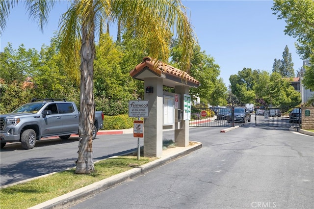 view of asphalt street with a gate, curbs, and a gated entry
