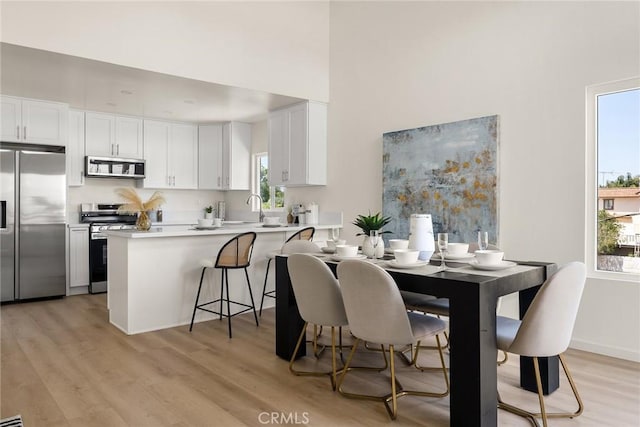 dining area featuring light wood finished floors and a towering ceiling