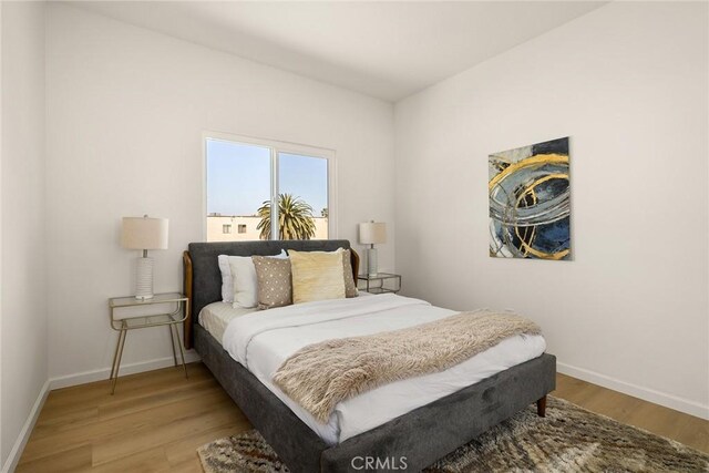 bedroom with light wood finished floors and baseboards