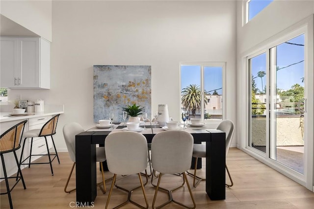 dining room featuring a high ceiling and light wood-style floors
