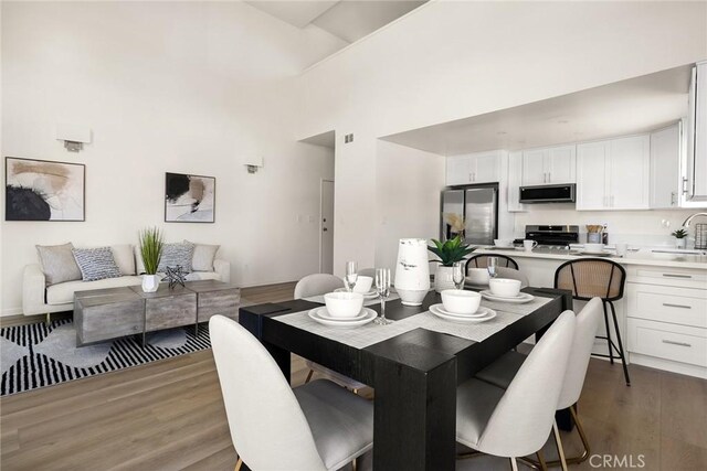dining space featuring wood finished floors and a high ceiling