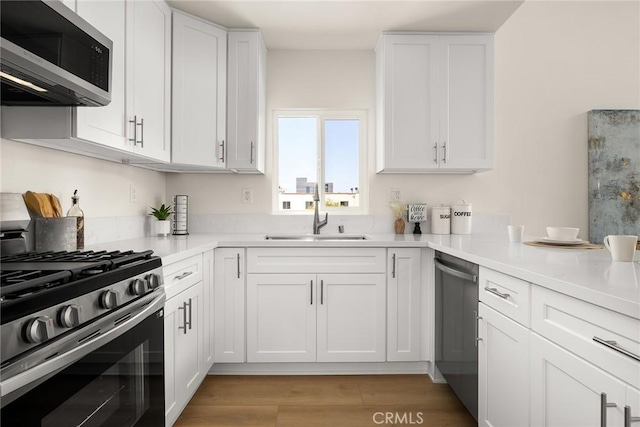 kitchen with stainless steel appliances, a sink, and white cabinetry