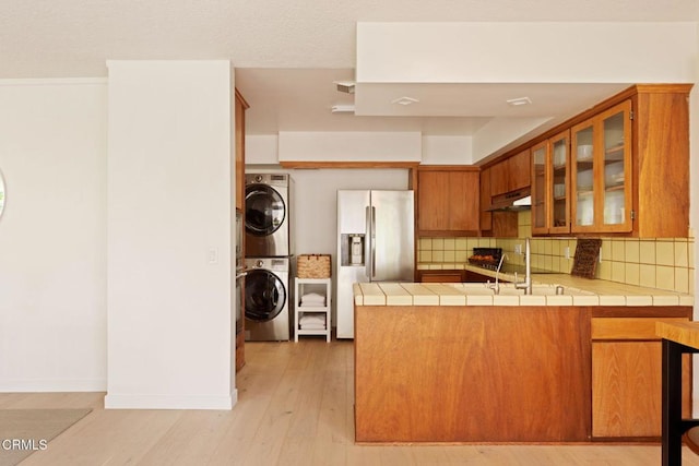 756 Linda Vista Ave, Pasadena, CA 91103 - kitchen featuring stainless steel refrigerator with ice dispenser, stacked washer / drying machine, under cabinet range hood, tile countertops, and brown cabinetry