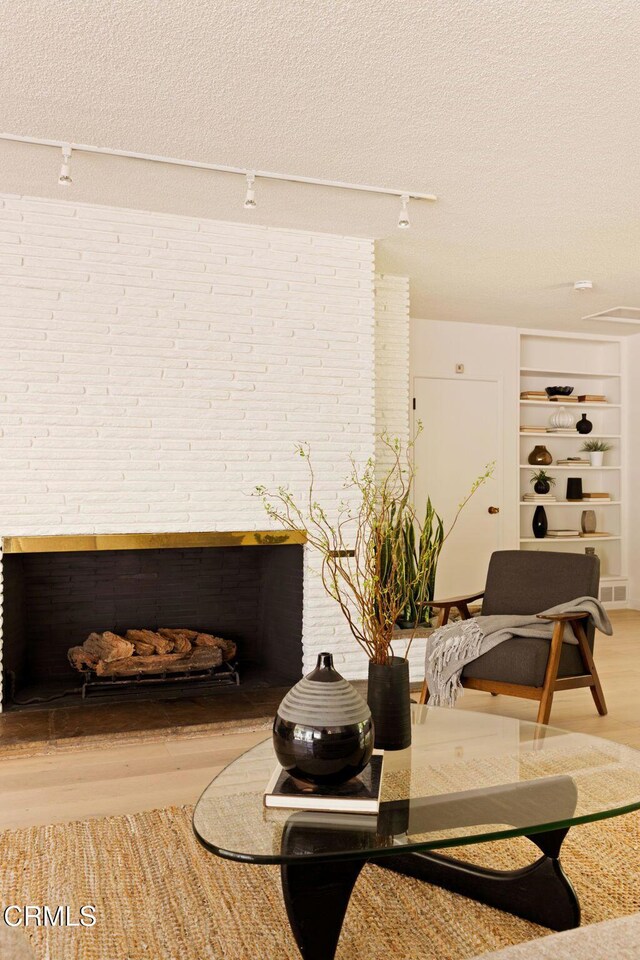 756 Linda Vista Ave, Pasadena, CA 91103 - detailed view of rail lighting, wood finished floors, a textured ceiling, a fireplace, and brick wall