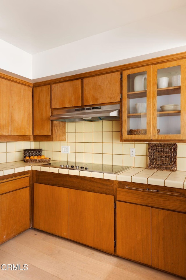 756 Linda Vista Ave, Pasadena, CA 91103 - kitchen with under cabinet range hood, tasteful backsplash, brown cabinetry, and tile countertops