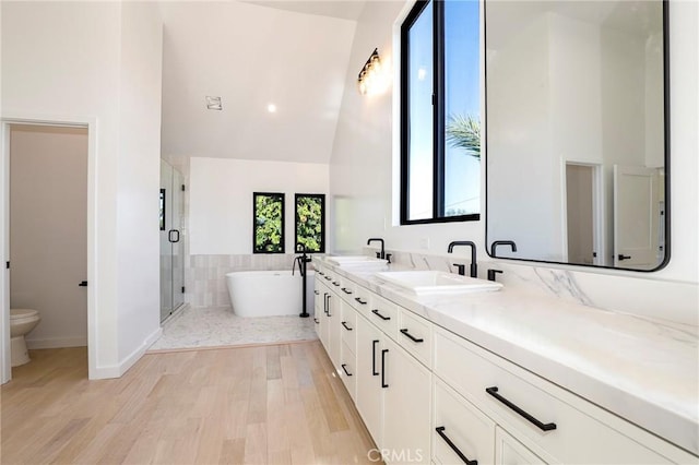 5633 E Deborah St, Long Beach, CA 90815 - bathroom featuring toilet, a freestanding tub, double vanity, a shower stall, and wood finished floors