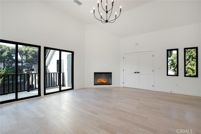 5633 E Deborah St, Long Beach, CA 90815 - unfurnished living room featuring high vaulted ceiling, a chandelier, light wood-style floors, baseboards, and a glass covered fireplace