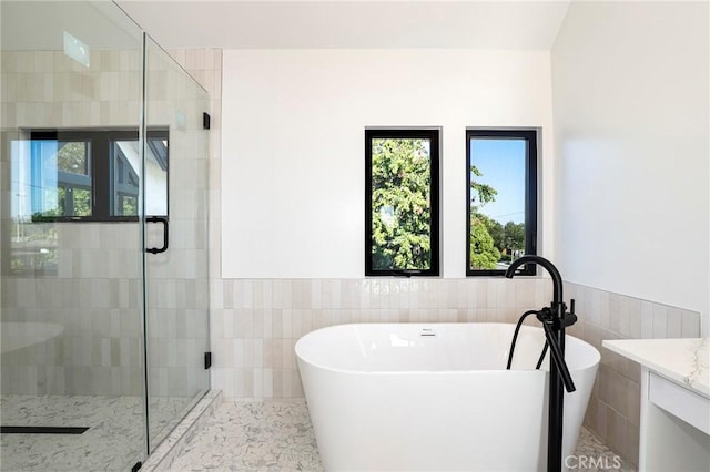 5633 E Deborah St, Long Beach, CA 90815 - full bathroom featuring tile walls, a soaking tub, a shower stall, vanity, and a wainscoted wall