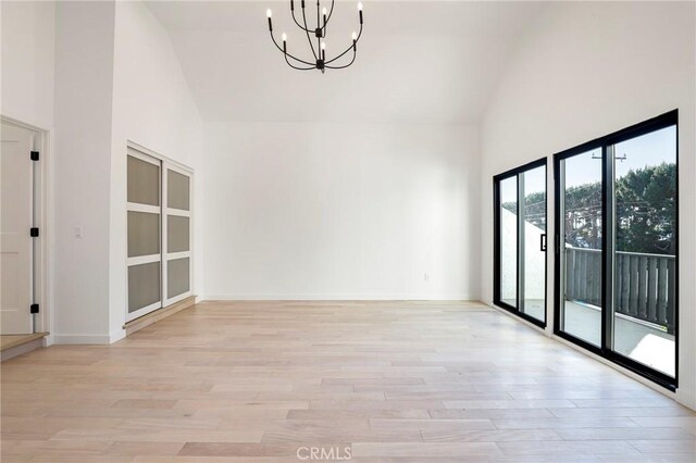 5633 E Deborah St, Long Beach, CA 90815 - empty room featuring high vaulted ceiling, a chandelier, light wood-style flooring, and baseboards