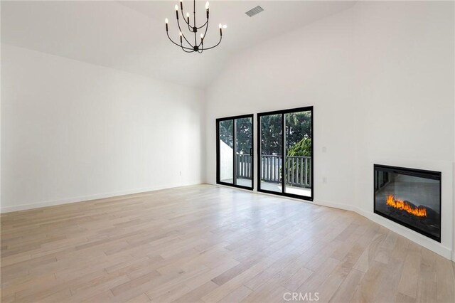 5633 E Deborah St, Long Beach, CA 90815 - unfurnished living room with high vaulted ceiling, a chandelier, light wood-type flooring, a glass covered fireplace, and baseboards