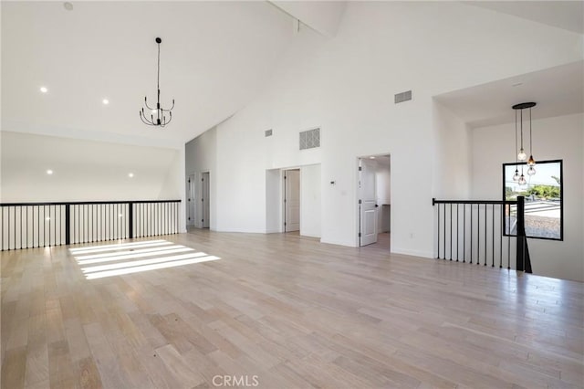 5633 E Deborah St, Long Beach, CA 90815 - unfurnished living room with high vaulted ceiling, a chandelier, light wood-style floors, and baseboards