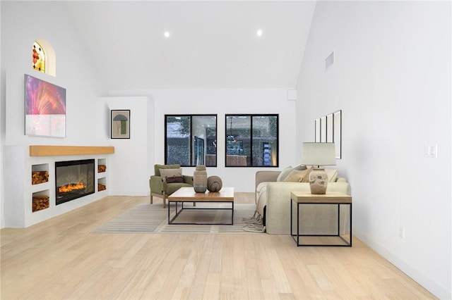 5633 E Deborah St, Long Beach, CA 90815 - living area with high vaulted ceiling, light wood-style flooring, a glass covered fireplace, recessed lighting, and baseboards