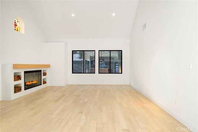 5633 E Deborah St, Long Beach, CA 90815 - unfurnished living room with high vaulted ceiling, wood finished floors, a glass covered fireplace, and recessed lighting