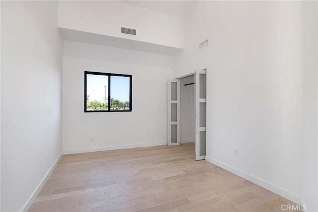 5633 E Deborah St, Long Beach, CA 90815 - unfurnished bedroom with light wood-type flooring, baseboards, and a towering ceiling