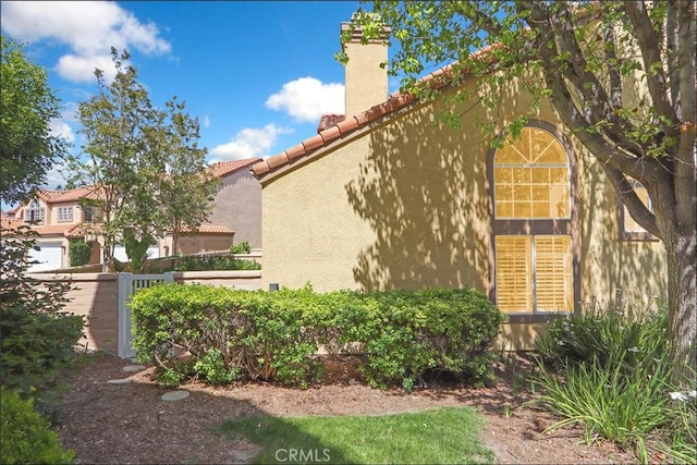 48 Via Athena, Aliso Viejo, CA 92656 - view of side of property with a tile roof, a chimney, and stucco siding
